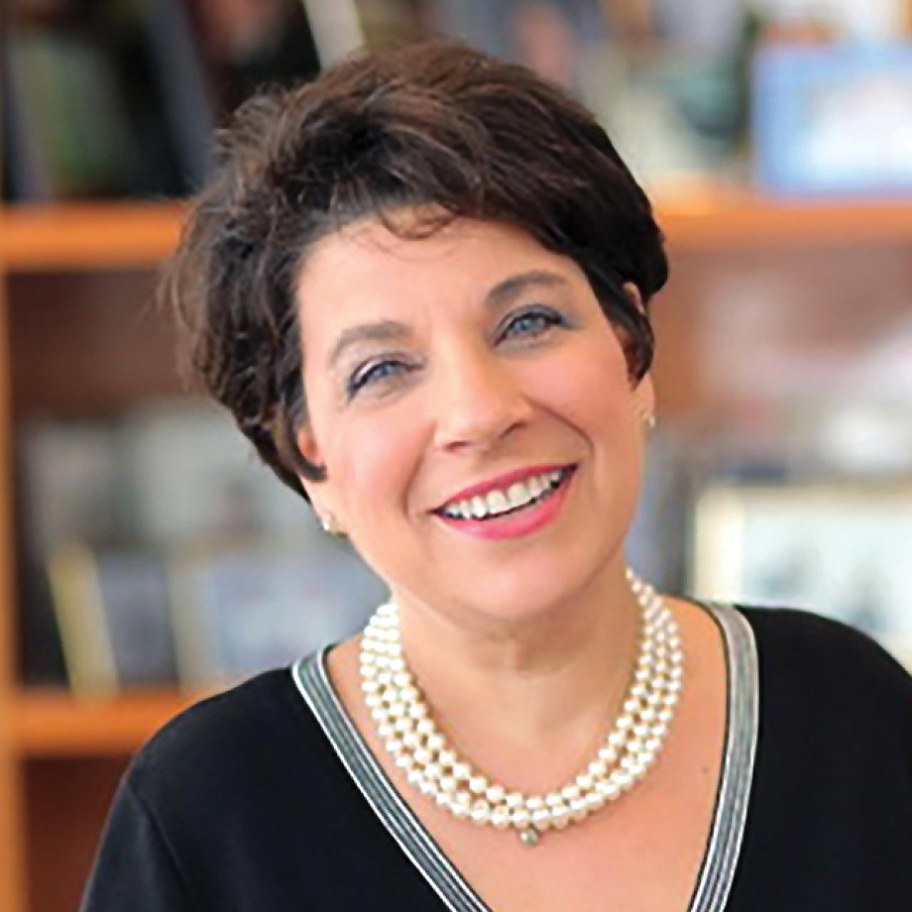 Portrait of Cory Abate-Shen smiling in front of bookshelves.