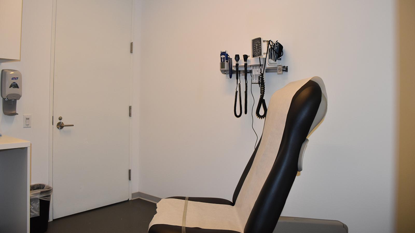 Medical examination room with equipment and observation window.