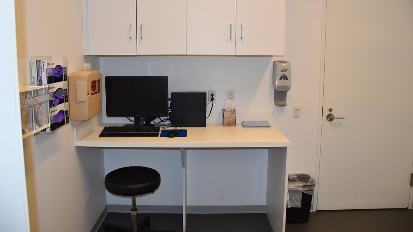 Medical examination room with equipment and observation window.