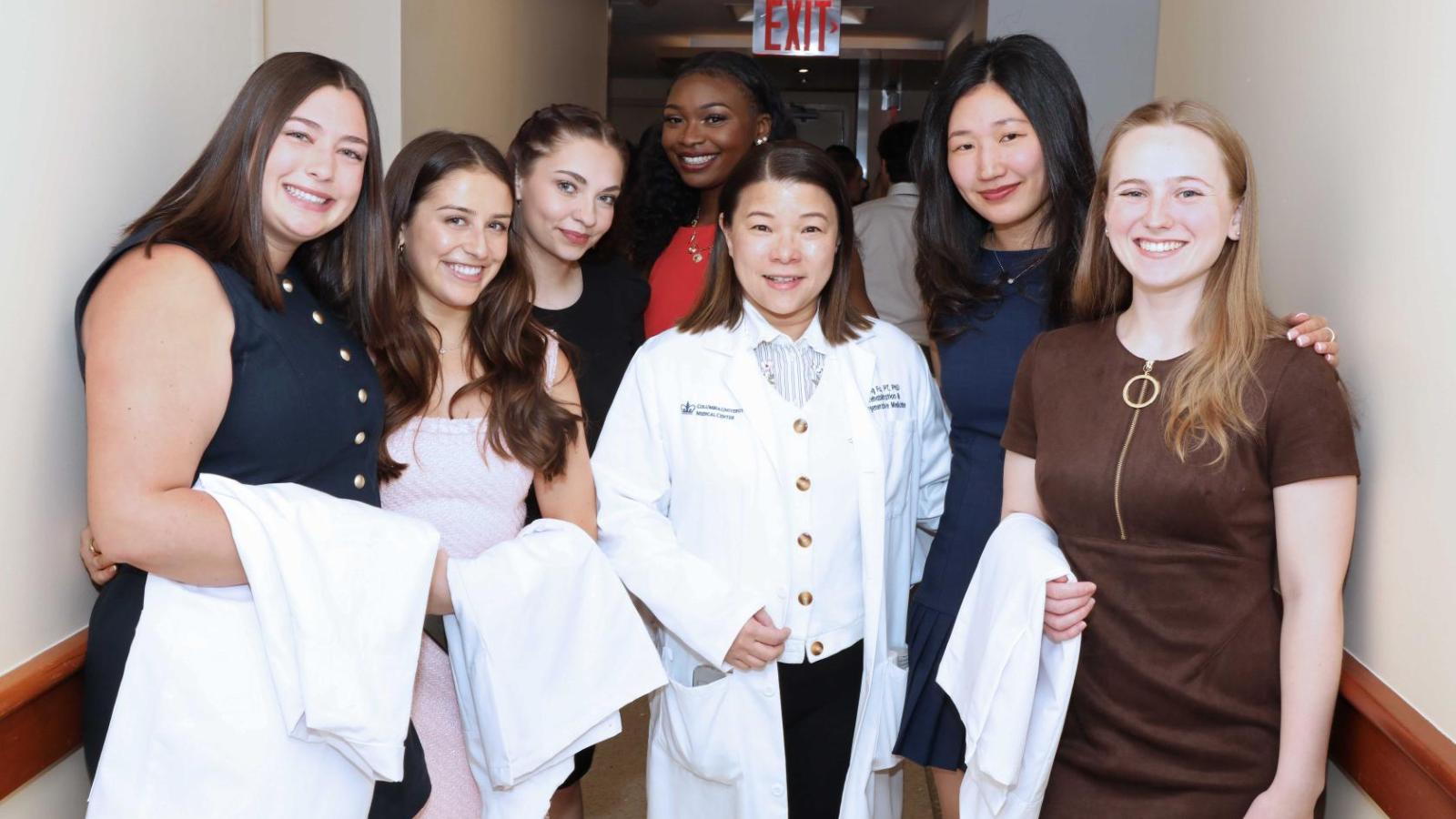 Doctor of Physical Therapy students and faculty pose together holding white coats during a Columbia University white coat ceremony.