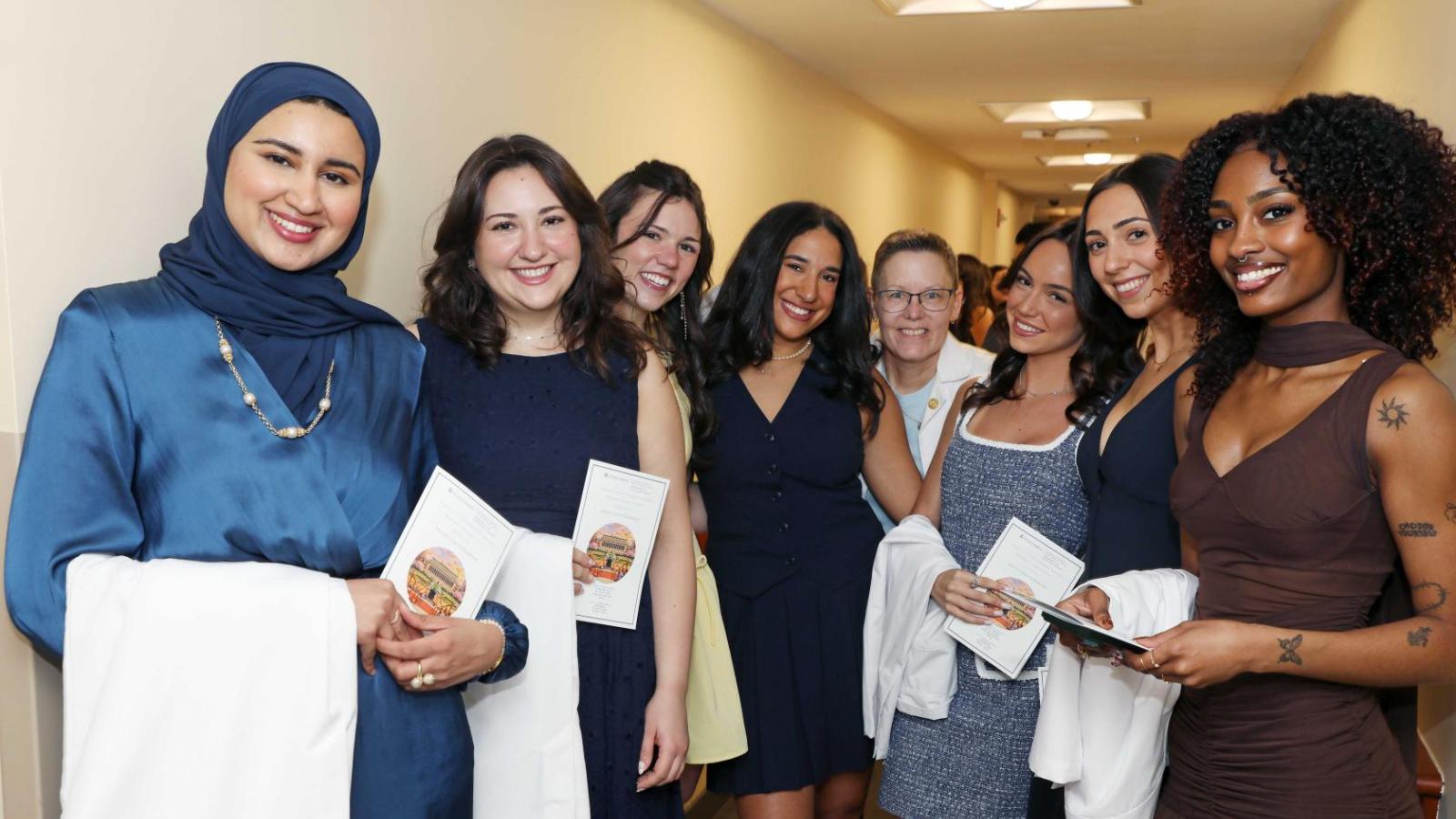 Doctor of Physical Therapy students and faculty pose together holding white coats during a Columbia University white coat ceremony.