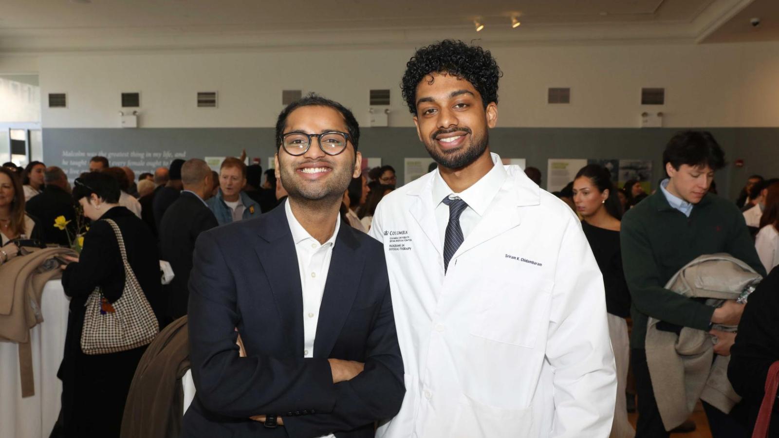 Columbia physical therapy student in a white coat poses with a guest during the white coat ceremony reception.