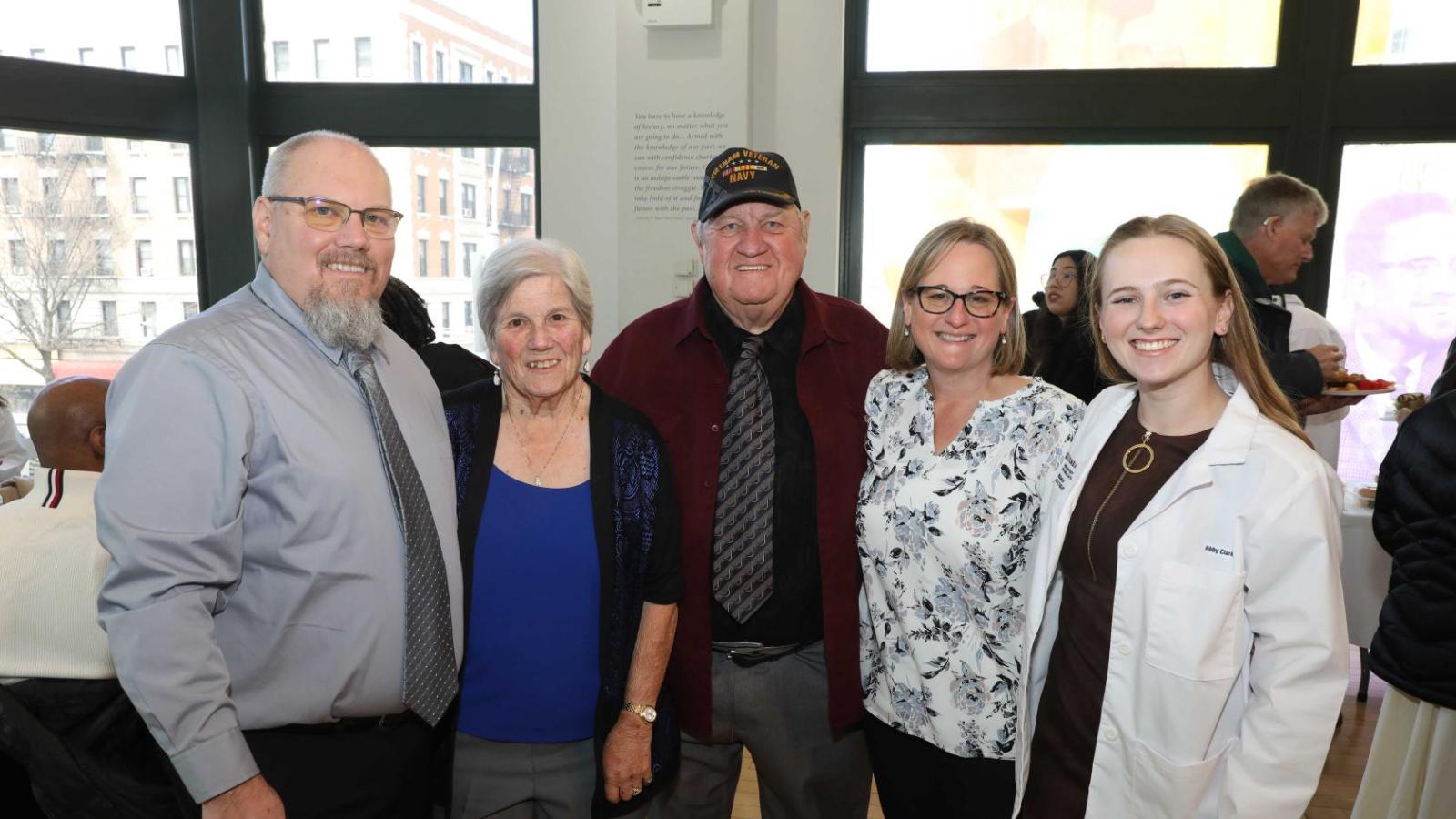 Columbia physical therapy student in a white coat poses with family members during the white coat ceremony reception.