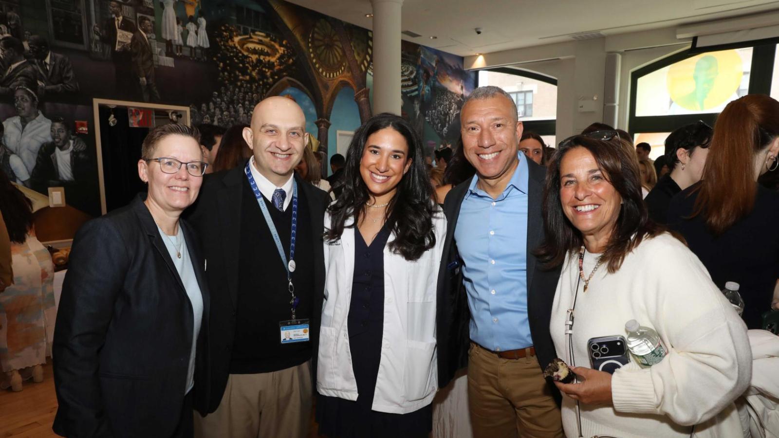 Columbia physical therapy faculty and family members pose with a student in a white coat during the white coat ceremony reception.
