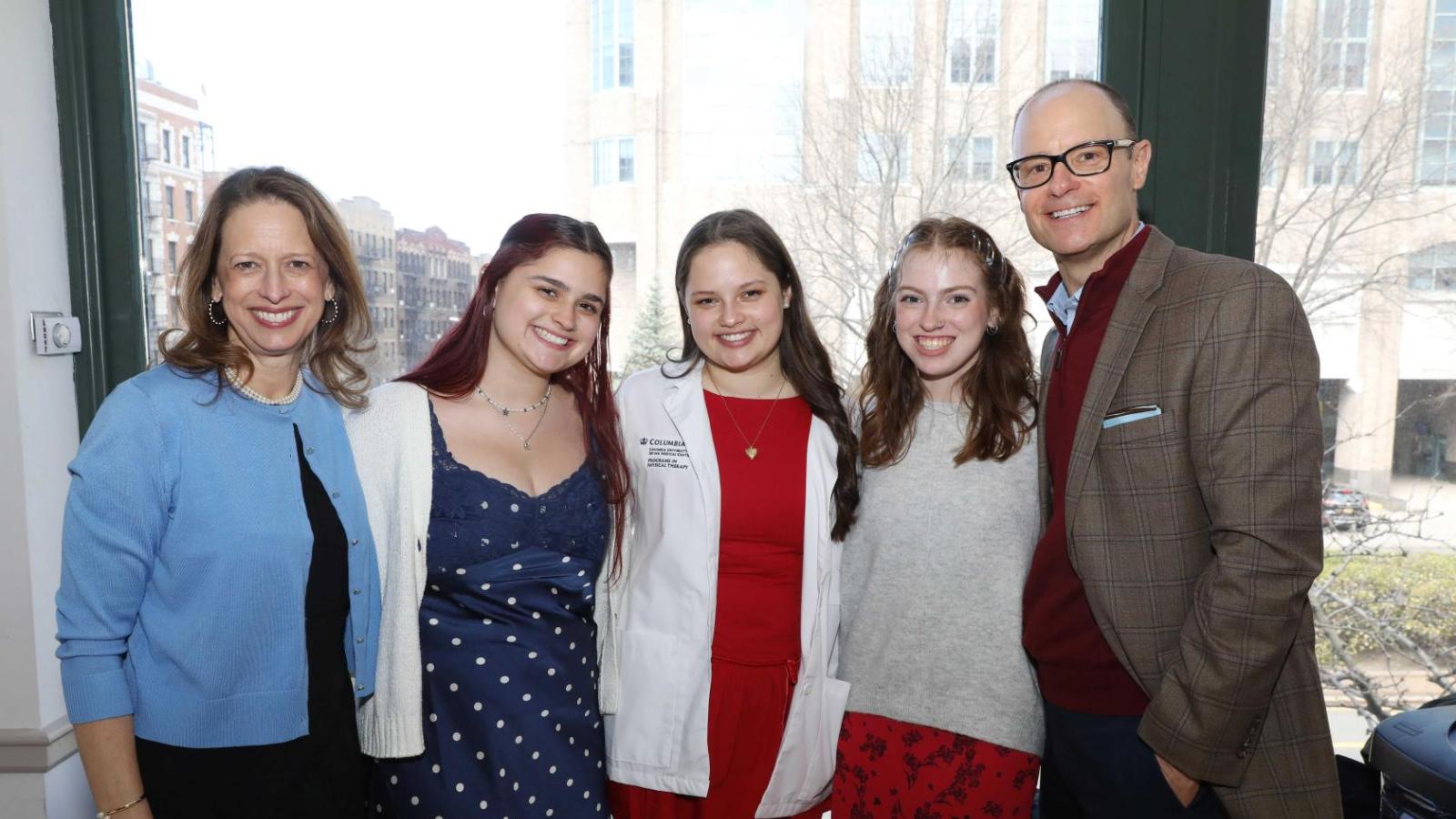 Columbia physical therapy student in a white coat poses with family members during the white coat ceremony reception.
