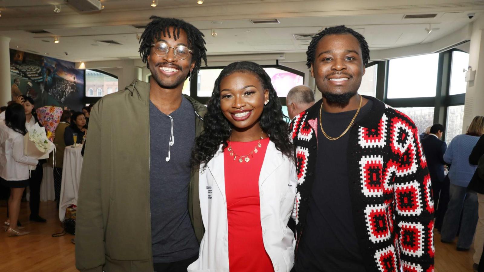 Columbia physical therapy student in a white coat poses with family members during the white coat ceremony reception.