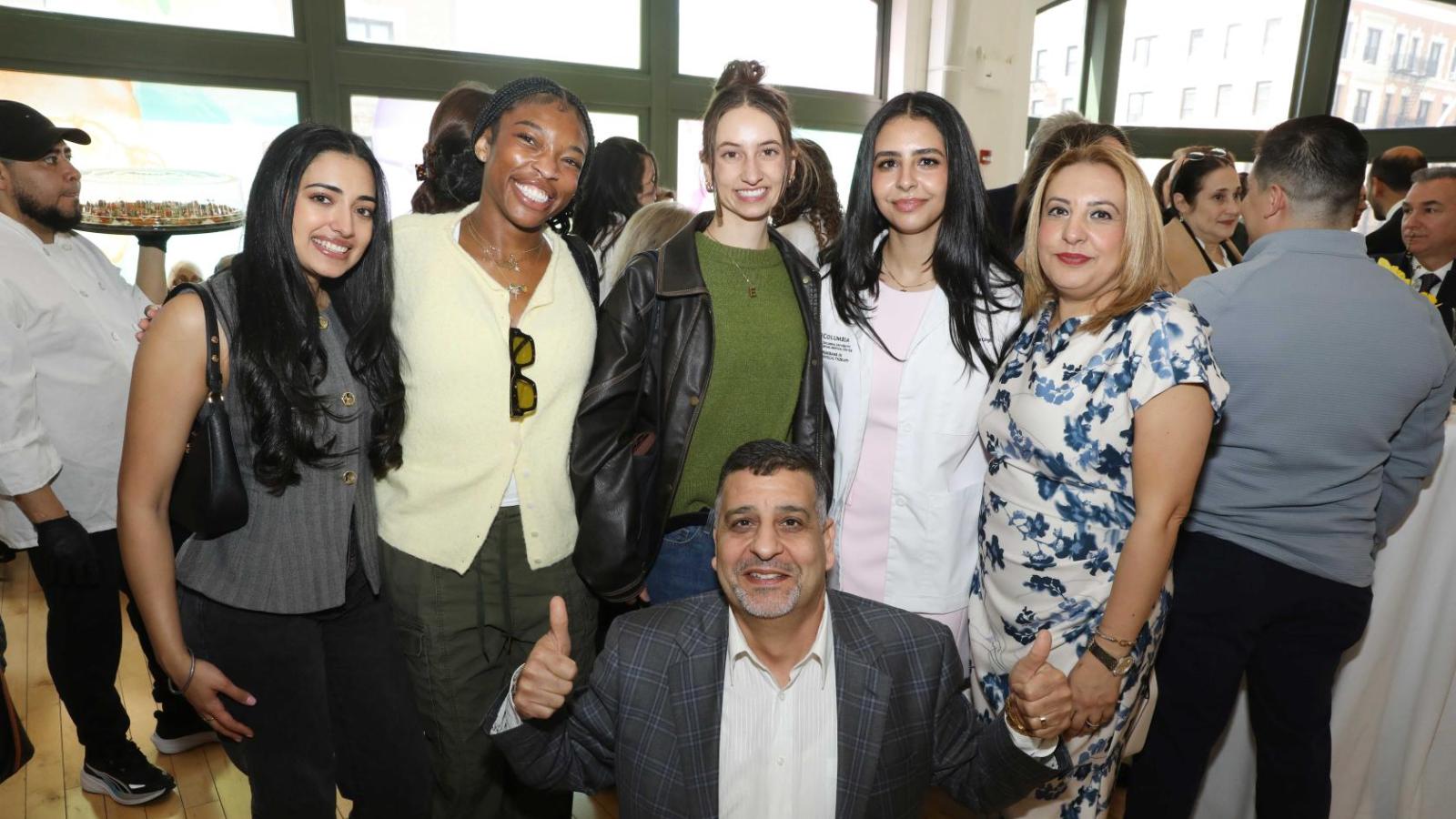 Multiple Columbia physical therapy students, including one in a white coat, pose with family members during the white coat ceremony reception.