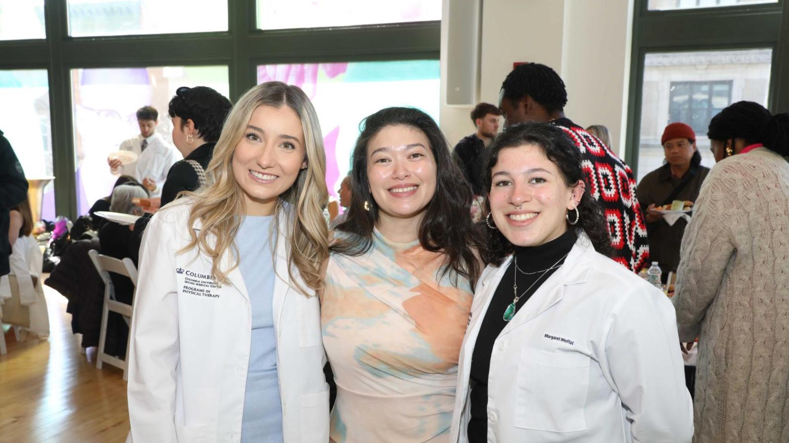 Columbia physical therapy students in white coats pose together at the white coat ceremony reception.