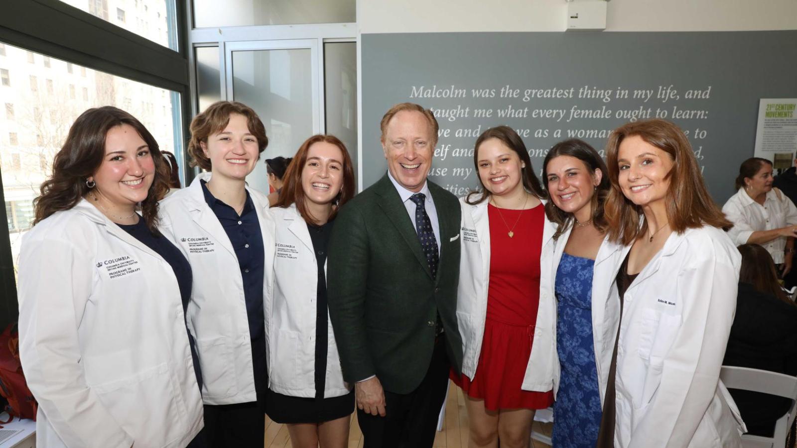 Columbia physical therapy students in white coats pose with a faculty member during the white coat ceremony reception.