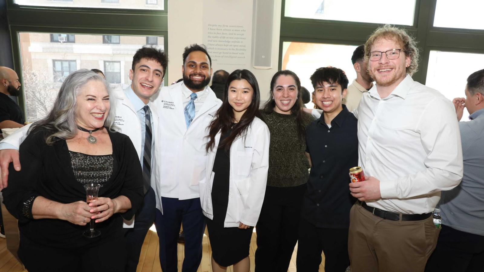 Columbia physical therapy students in white coats pose with a family member during the white coat ceremony reception.