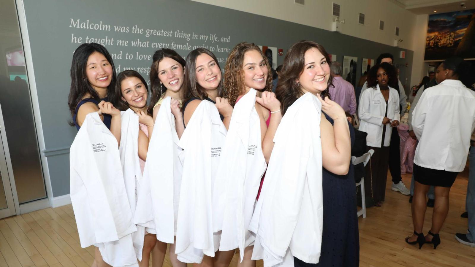 Doctor of Physical Therapy students pose together holding white coats during a Columbia University white coat ceremony.