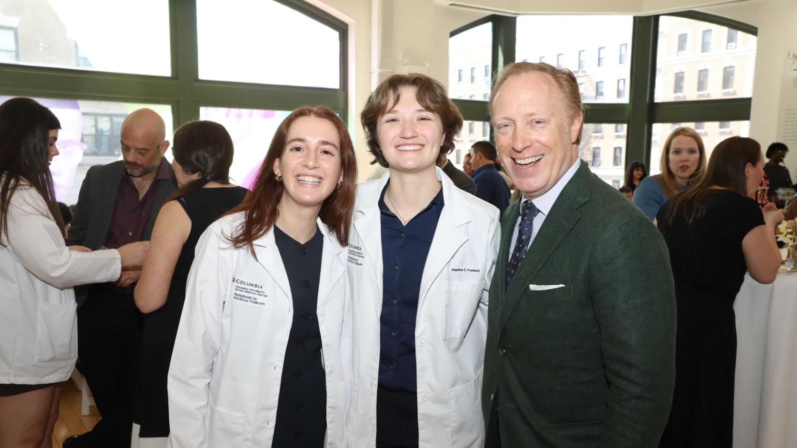 Columbia physical therapy students in white coats pose with a faculty member during the white coat ceremony reception.