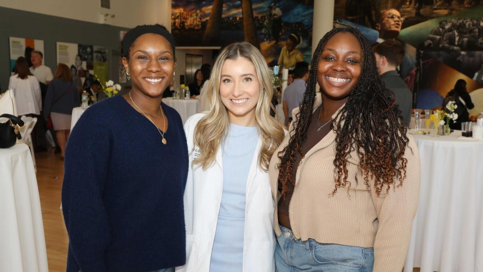 Columbia physical therapy student in a white coat poses with classmates at the white coat ceremony reception.