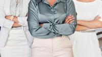 A diverse team of women with their arms crossed in the office.