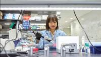 Woman in a lab coat holds a pipette in her hand