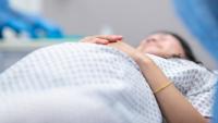 Pregnant woman in hospital gown laying on an examination table