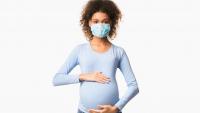 pregnant woman wearing mask and holding belly