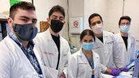Five researchers in the Department of Radiation Oncology stand next to each other wearing masks