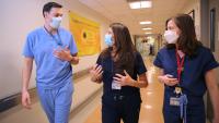 Three members of the Pulmonary and Critical Care Medicine Fellowship speak to each other in a hallway