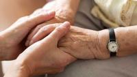 Nurse consoling her elderly patient by holding her hands