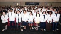 Doctor of Physical Therapy students at Columbia University pose together wearing white coats during their white coat ceremony.