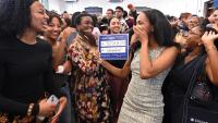 A woman holds a blue sign that says Columbia Psychiatry while her family cheers around her