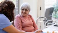 The senior adult woman asks her nurse for help organizing her medications