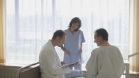 two doctors talking to patient at their bedside
