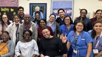 Group of medical residents and healthcare staff posing together, several wearing scrubs and stethoscopes.