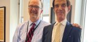 Two professionals in business attire posing together in an office.