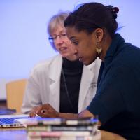 Two women look at a laptop.